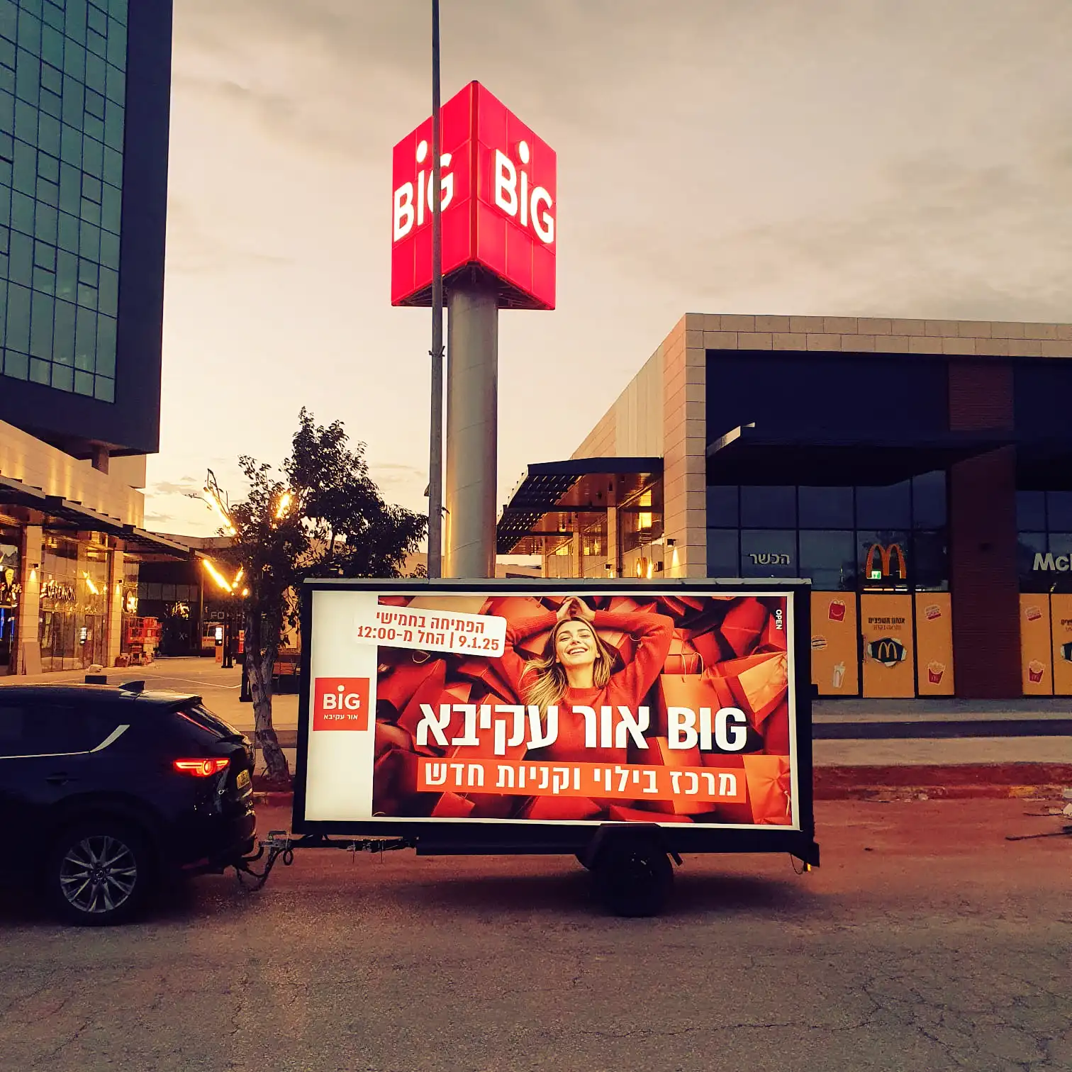 יחידת מסך לד ניידת מציגה את מודעת הפתיחה של BIG אור עקיבא מול הכניסה למתחם בשעת ערב